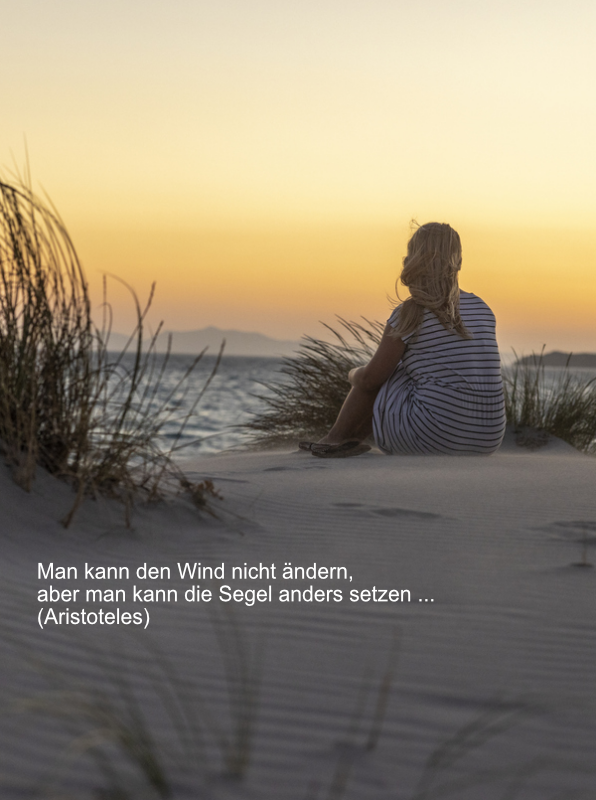 Frau am Strand blickt in den Sonnenuntergang
